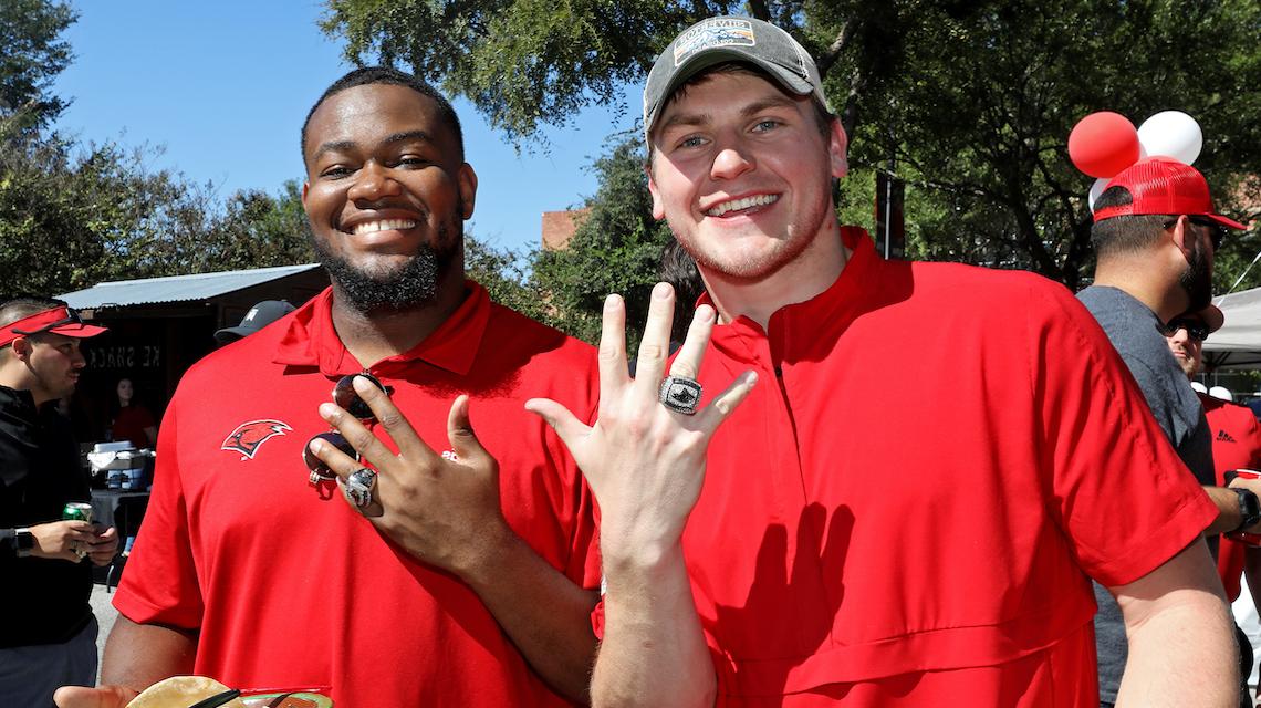 两名uw橄榄球校友在返校节上展示他们的分区冠军戒指